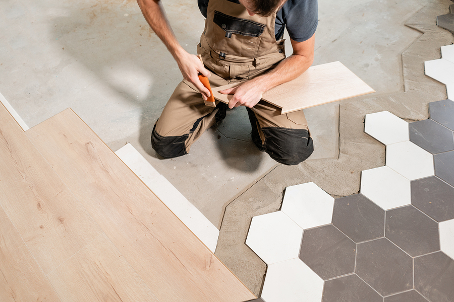 male worker installing new wooden laminate flooring. the combination of wood panels of laminate and ceramic tiles in the form of honeycomb